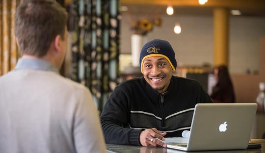 Person sitting at computer talking to advisor