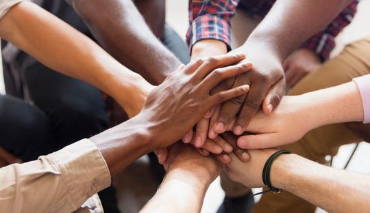 A group of people putting hands in a pile