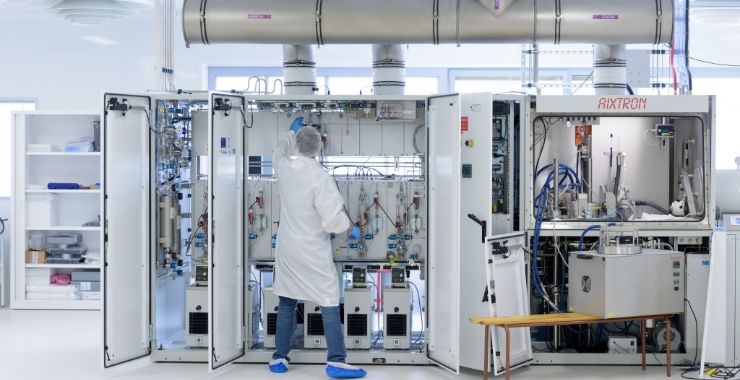 Student working on large machine while wearing a lab coat