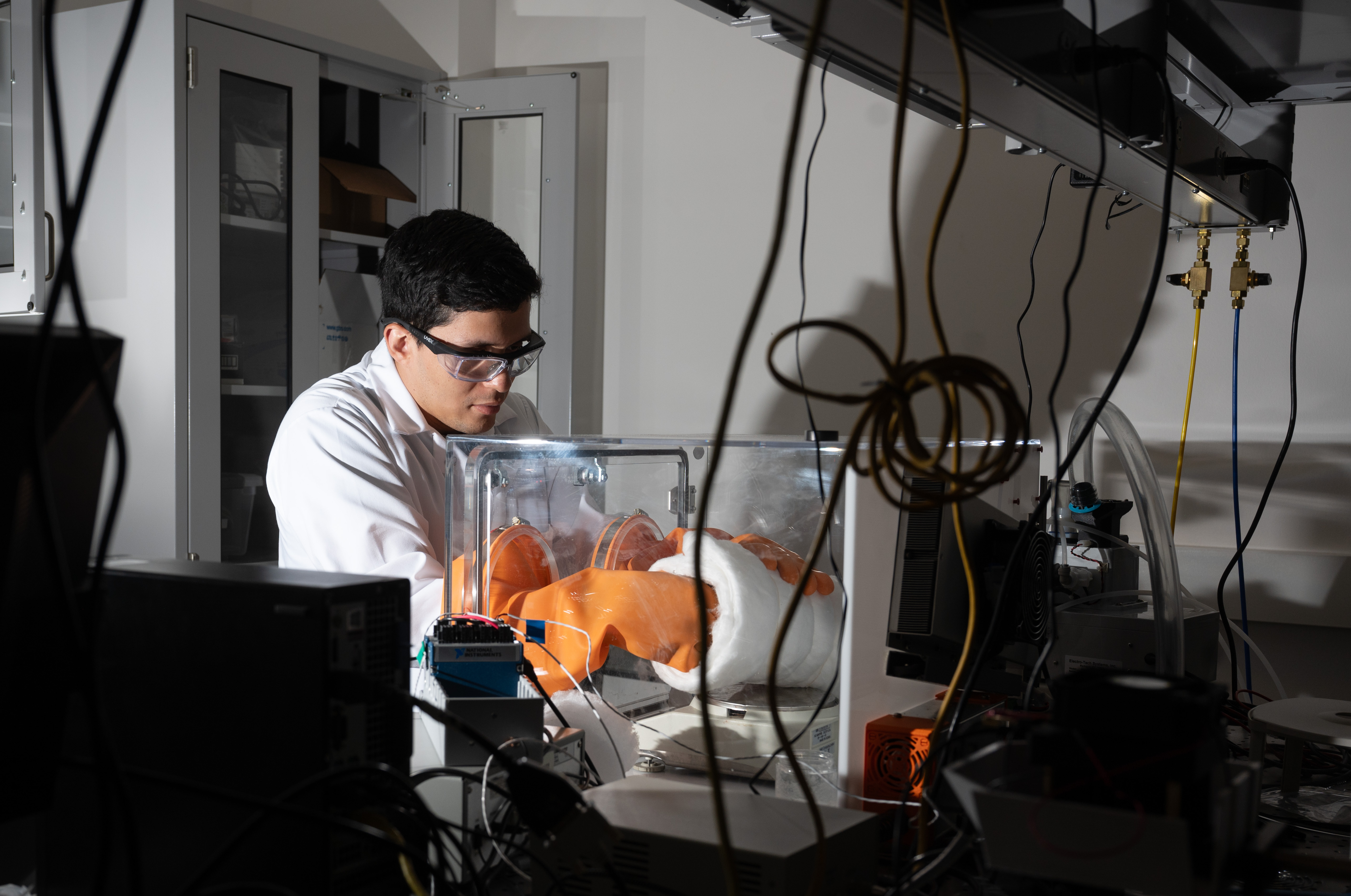 Man in white lab suit working with a research instrument in a lab